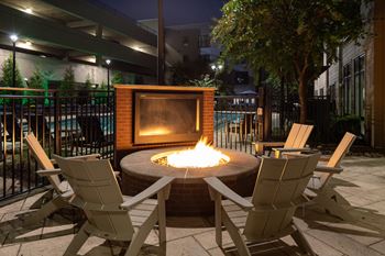 A fire pit with a fire burning in it surrounded by chairs.